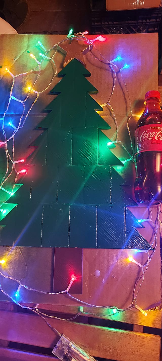 A 3D printed evergreen tree with string lights circling around it and a bottle of Coke Starlight for scale